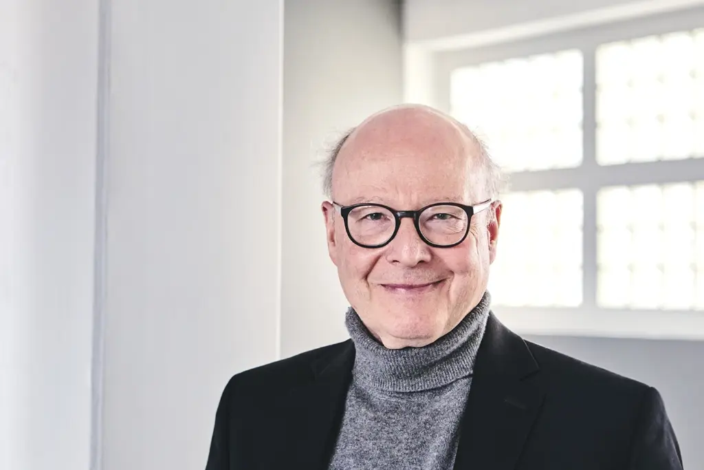 Querformatiges freundliches Portrait von Professor Doktor Michael Bordt SJ im hellen weißen Raum
